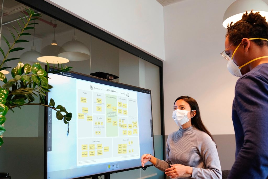 Team collaborating with digitized Lean System with visual collaboration tools on touchscreen with digital sticky notes