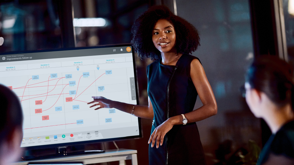 Business woman using digital touchscreen to scale visual management methodologies with the people-centered principles of Lean and Agile.