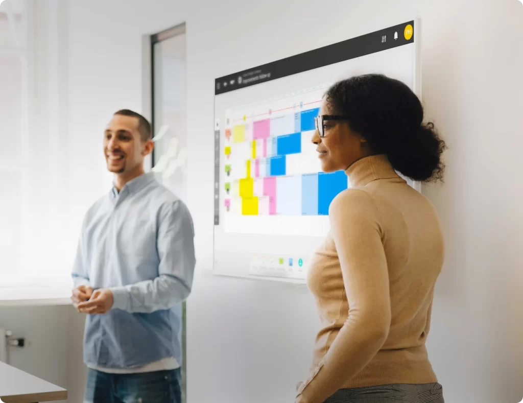 Photo of two team members presenting a planning on an iObeya digital board