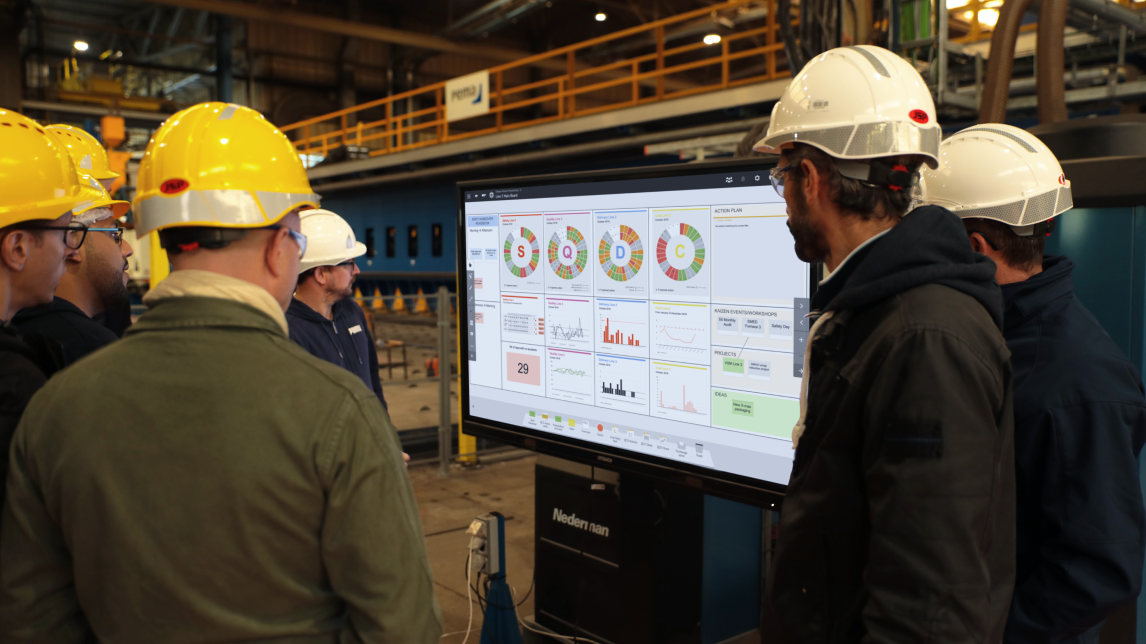 Une équipe de responsables de production évaluant les résultats sur leur panneau SQCDP numérisé.