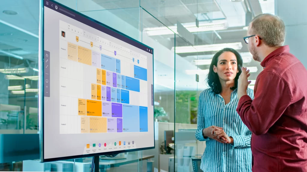 Head of Operational Excellence in a business office updating digital daily capacity management board to visually track project progress.