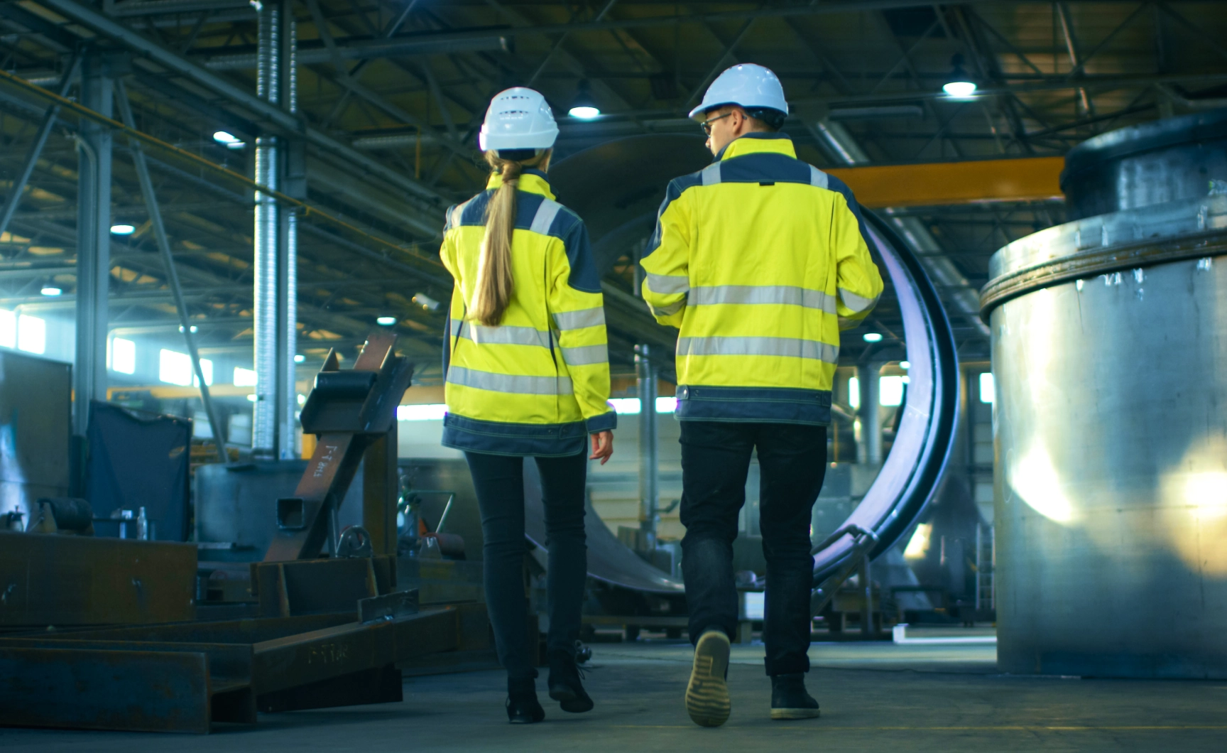 Employees in safety vests and hard hats walking on ShopFloor at Lean Manufacturing Enterprise