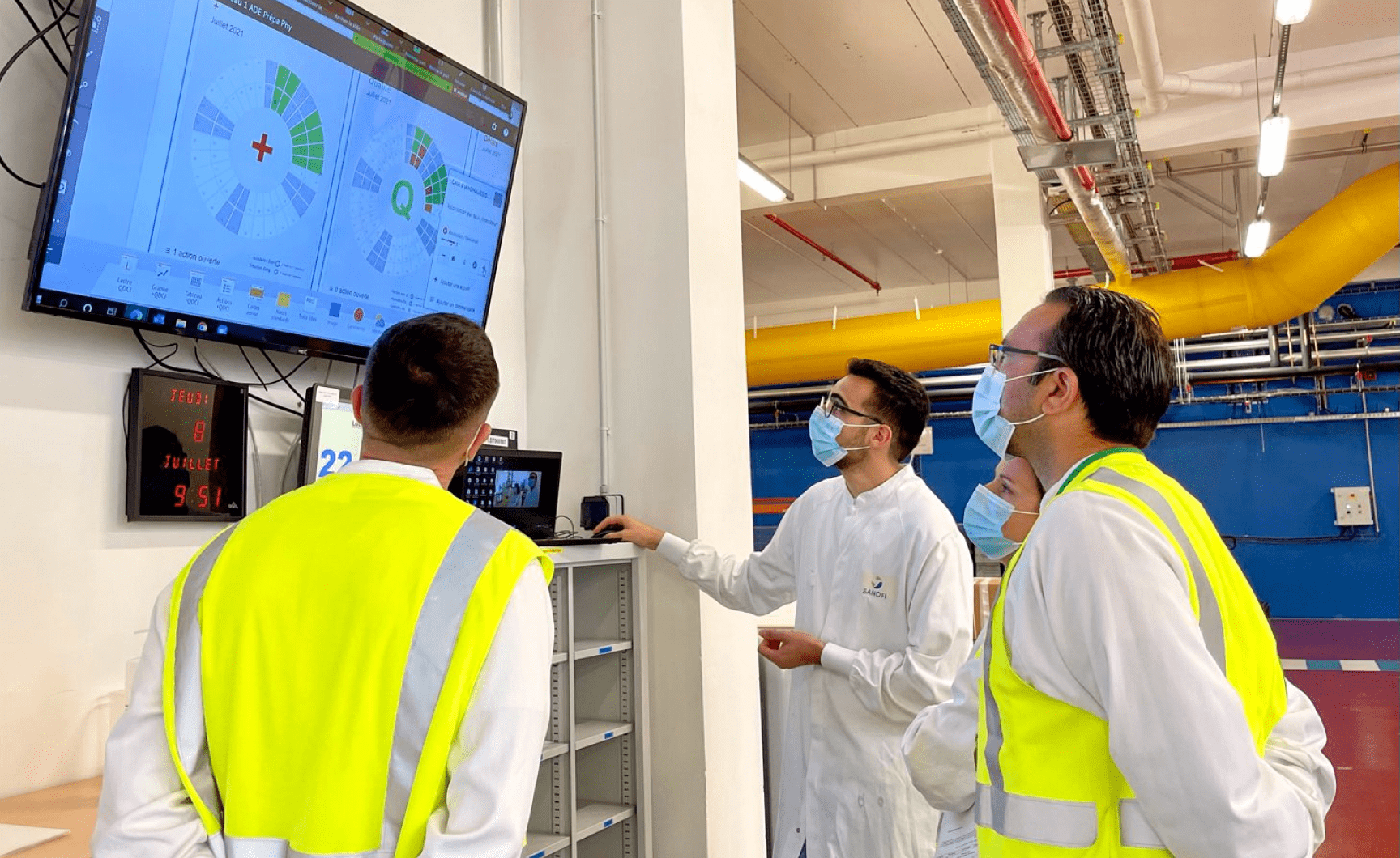 équipe dans une usine métant à jour des lettres SQCD digitalement dans iObeya sur un écran tactile pour une collaboration optimisée.