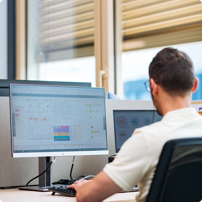 Engineer working with iObeya on dual monitors to manage design reviews, KPIs, and Lean Engineering processes